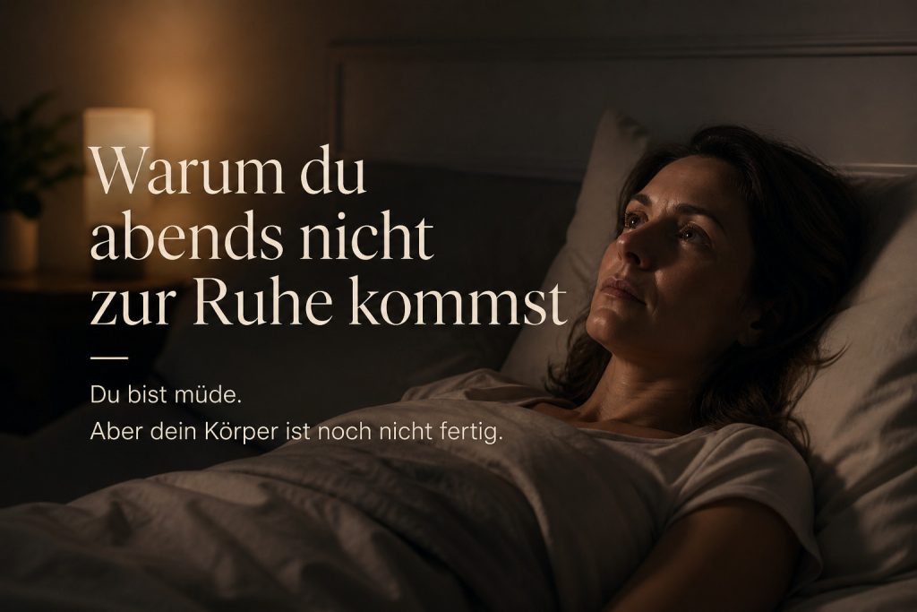 A calm, dimly lit bedroom at night. A woman in her 30s or 40s lies in bed, visibly tired but awake, eyes open, staring softly into the distance. Her body is still, but her face shows subtle inner tension and restlessness — not dramatic, but quietly present. The atmosphere is peaceful yet slightly charged, as if something unresolved is still active inside her. Soft, warm lighting with gentle shadows. Minimal, clean aesthetic, natural tones, no clutter. Cinematic, realistic, high detail, emotional depth. Add German text overlay in elegant, modern typography: “Warum du abends nicht zur Ruhe kommst Du bist müde. Aber dein Körper ist noch nicht fertig.” warum-komme-ich-abends-nicht-zu-ruhe